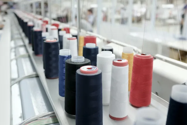 Cones of coloured thread lined up on an embroidery machine rack
